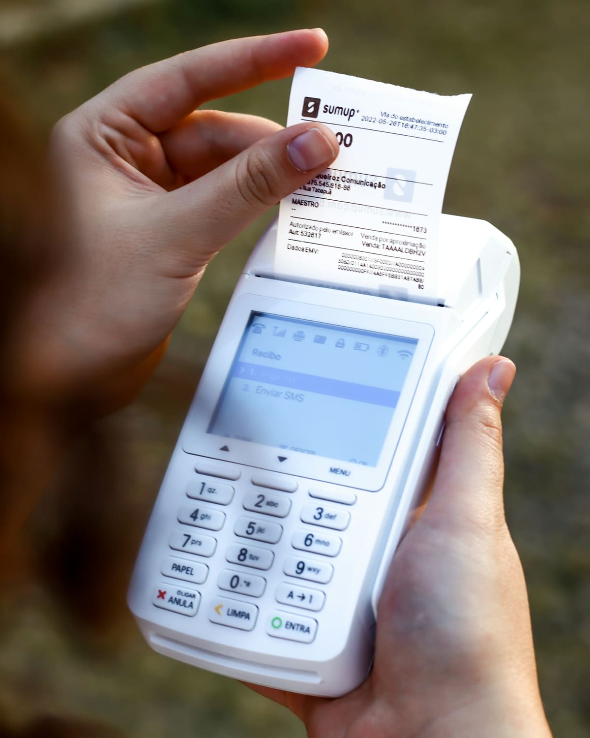 Close-up photograph of a hand holding a receipt coming out of a card terminal